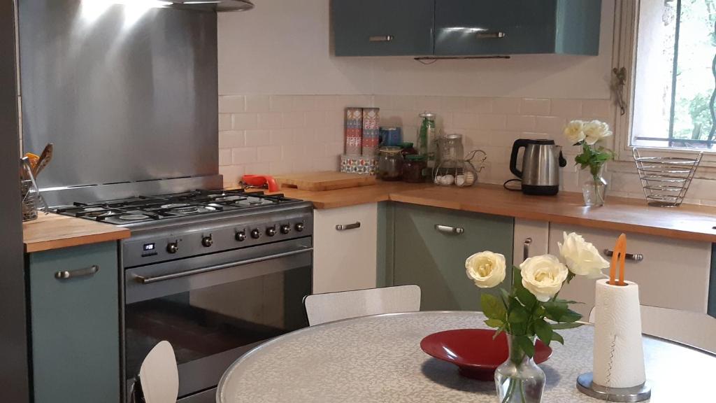 a kitchen with a stove and a table with flowers at Le Mas Nomade in Callian