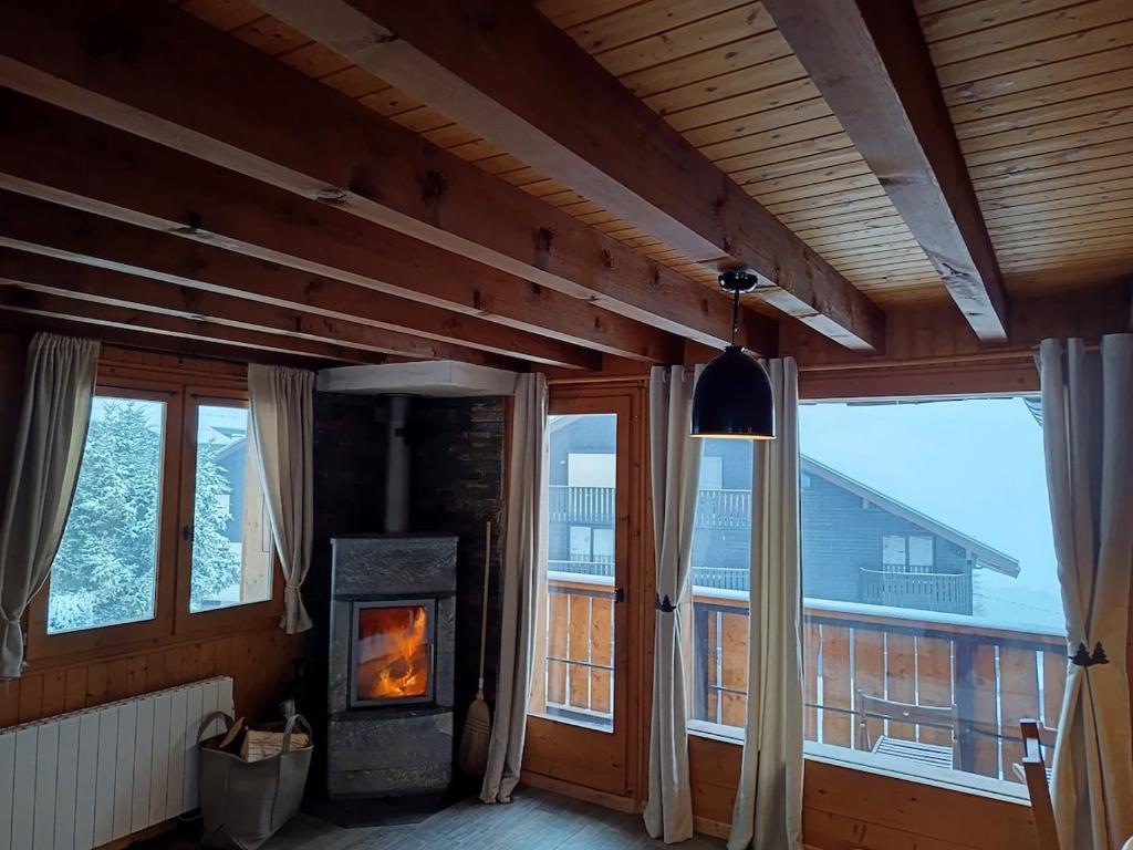 a woodburning stove in a room with a large window at Chalet au cœur de la station in Thollon