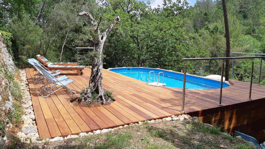 a wooden deck with a swimming pool next to a tree at Le Mas Nomade in Callian