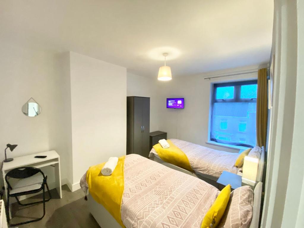 une chambre avec deux lits, un bureau et une fenêtre dans l'établissement Emerald Living, 4 bedrooms, sleeps 6, free parking in the heart of Swansea!, à Swansea
