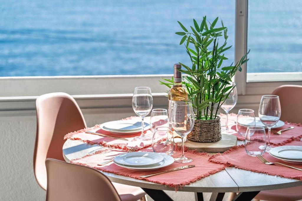 une table avec des verres à vin et une plante dessus dans l'établissement Appart le Grand Bleu Saint Aygulf, à Fréjus