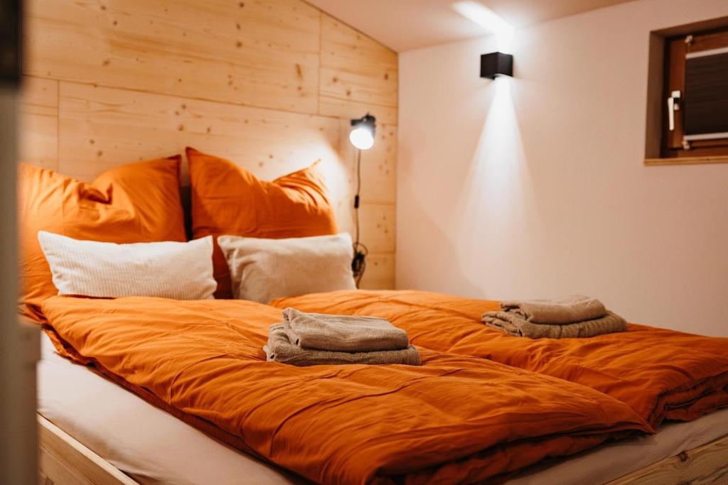 a large orange bed with two towels on it at Lodge mit Sauna & Seeblick für Naturliebhaber in Diemelsee