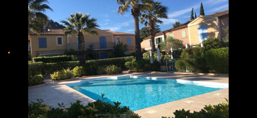 - une piscine dans une cour avec des palmiers et des maisons dans l'établissement Mazet 33, au Plan-de-la-Tour