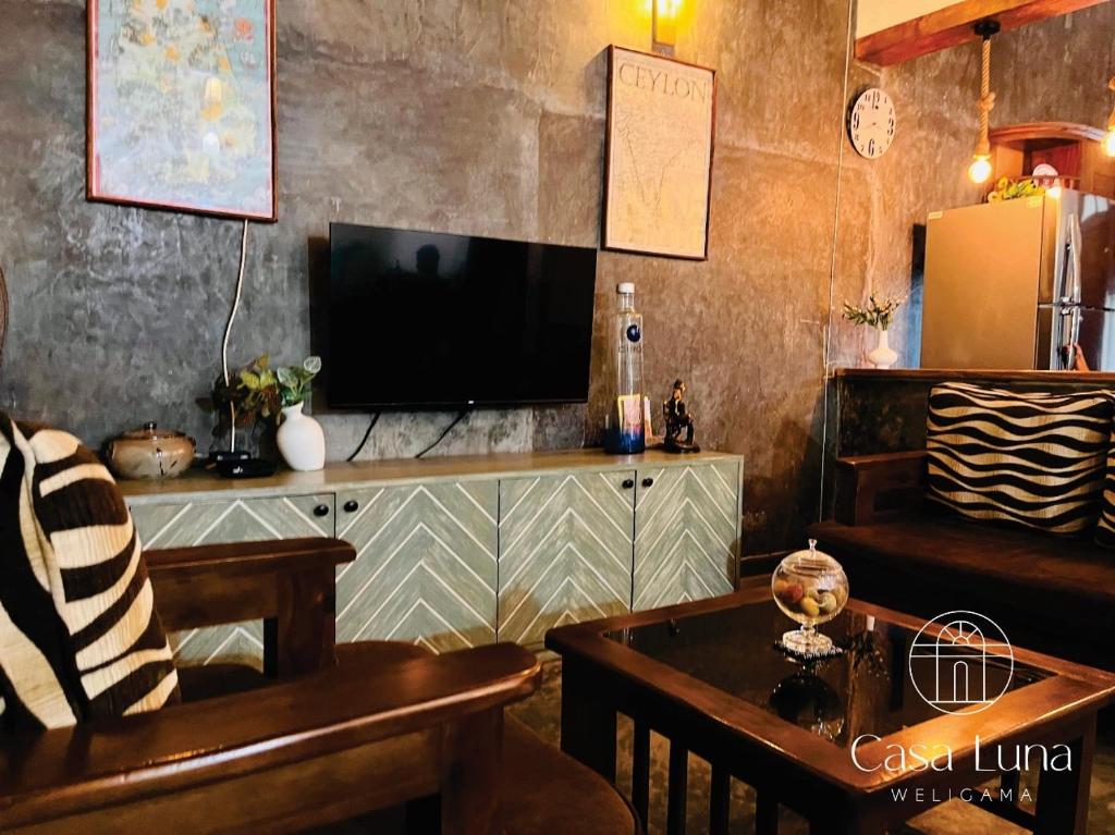 een woonkamer met een televisie en een tafel bij Casa Luna Weligama in Weligama