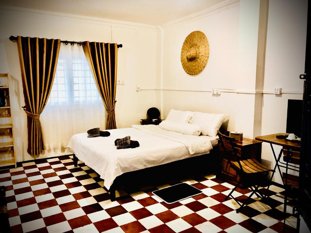 Un dormitorio con una cama y un suelo de cuadros. en New Central Villa Garden Apart & swimming pool, en Kampot