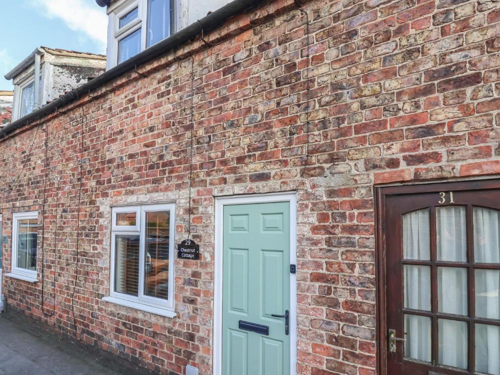 a brick building with a green door and a window at Chestnut Cottage in Wetwang