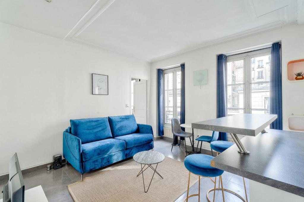 un salon avec un canapé bleu et une table dans l'établissement GuestReady - Modern comfort in Les Batignolles, à Paris