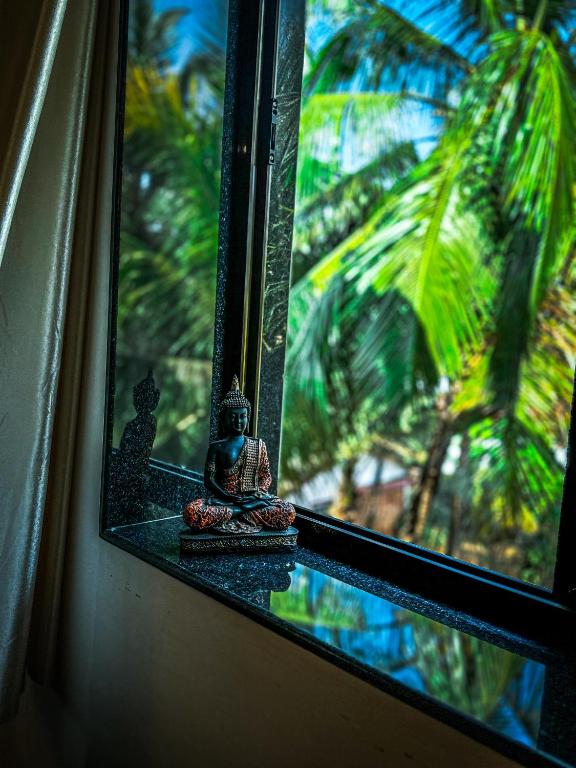 a window with a view of a palm tree at 1BHK Apartment at Honeydew 8 by Goaround Homes in Vagator