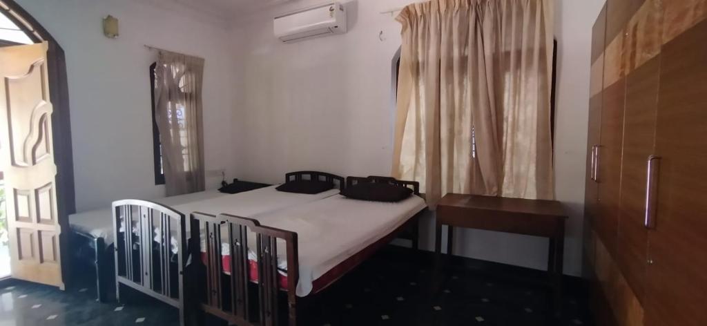 a bedroom with a bed and a table and a window at Aryabhadhra Cottages 7, Room-4 in Ernakulam