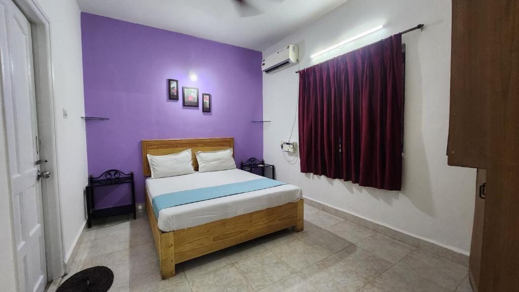 a bedroom with a bed with a purple wall at Krishna holidays in Calangute