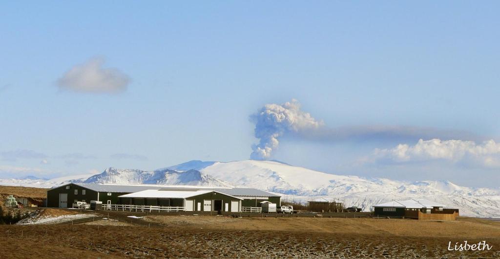 a building in front of a volcano with smoke at Skeiðvellir Villa in Hella