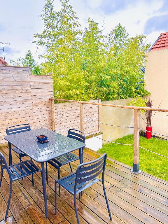 une table et deux chaises sur une terrasse en bois dans l'établissement Cosy Maison aux portes de paris, à Colombes