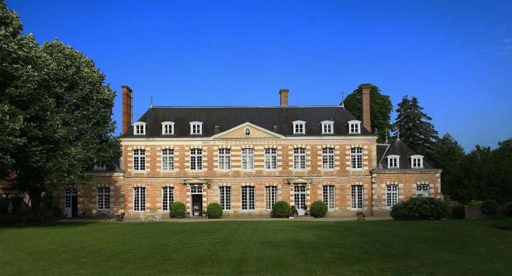 un gran edificio de ladrillo con un gran césped delante en Château de la Giraudière, en Villeny