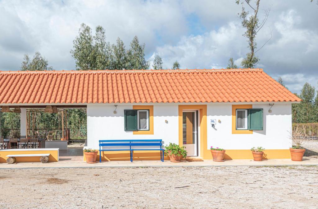 una piccola casa con tetto arancione e panca blu di Casa do Caçador a Sesimbra
