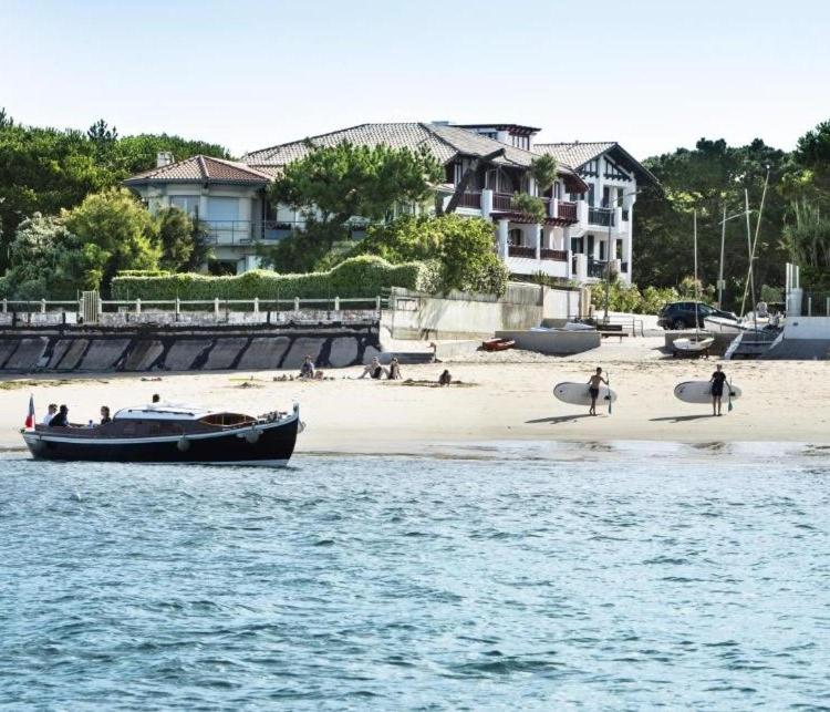 a group of people on a beach with a boat at Villa du Pyla in Pyla-sur-Mer