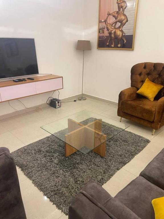 un soggiorno con tavolino da caffè in vetro e due sedie di Villa pacha a Cotonou