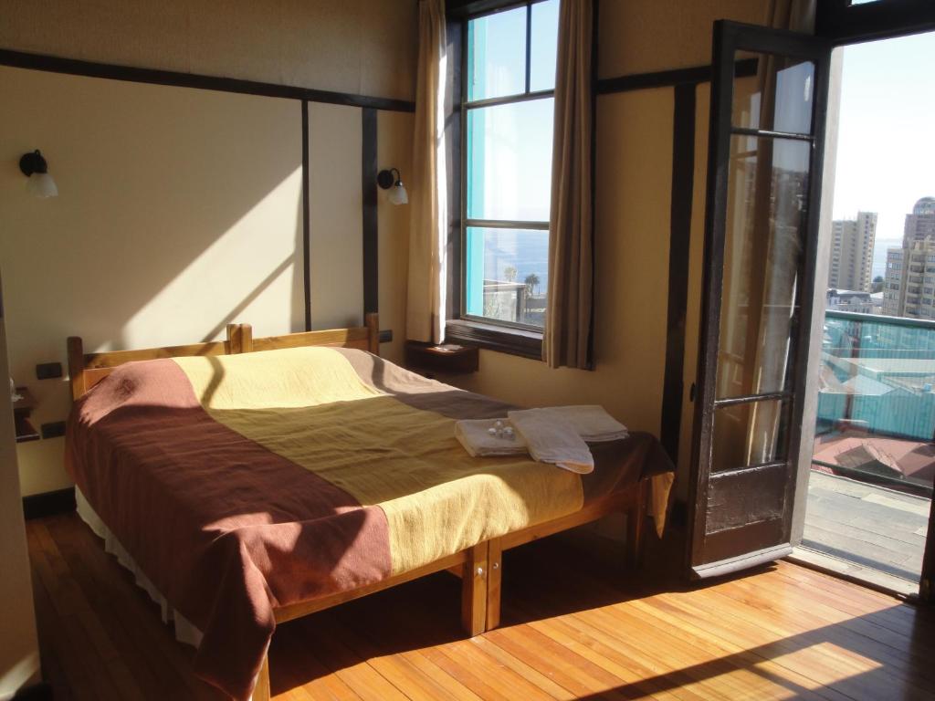 um quarto com uma cama e uma janela aberta em The Travelling Chile em Valparaíso