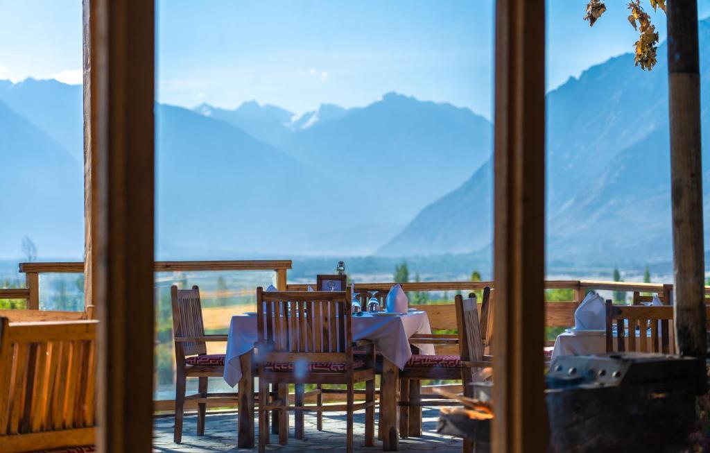 a table and chairs on a balcony with a view of mountains at Stone Hedge Hotel in Nubra