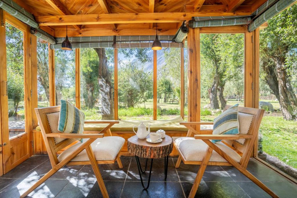 a screened in porch with two chairs and a table at Stone Hedge Hotel in Nubra