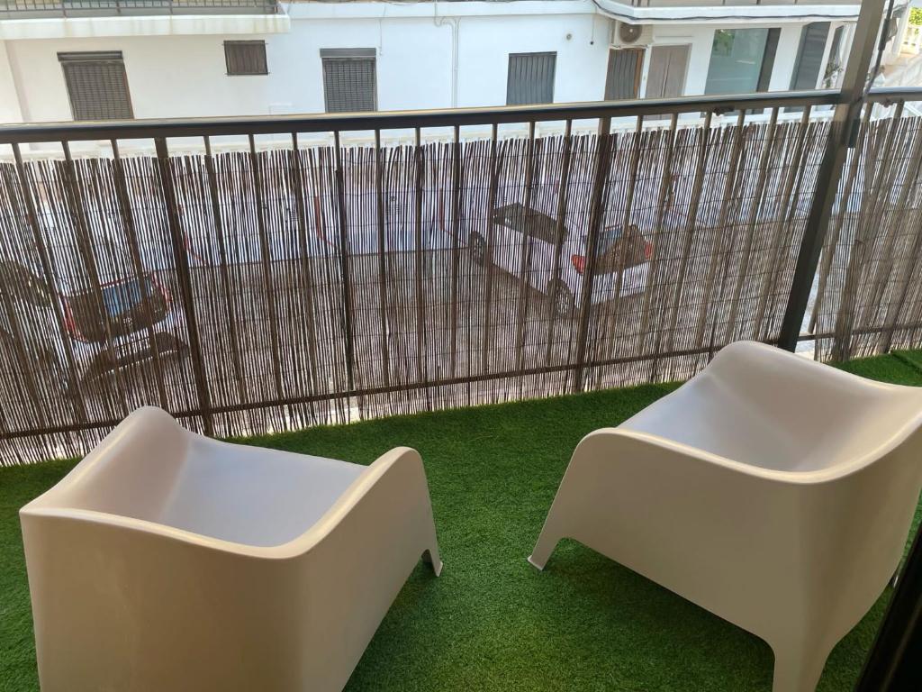 two white chairs on a balcony with a fence at Apartamento Neptuno A4 in Puebla de Farnals