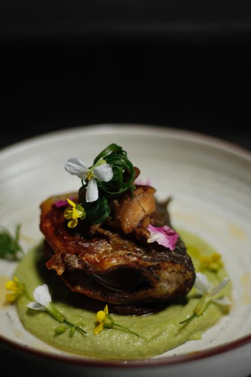 a white plate with a piece of meat with flowers on it at Stone Hedge Hotel in Nubra
