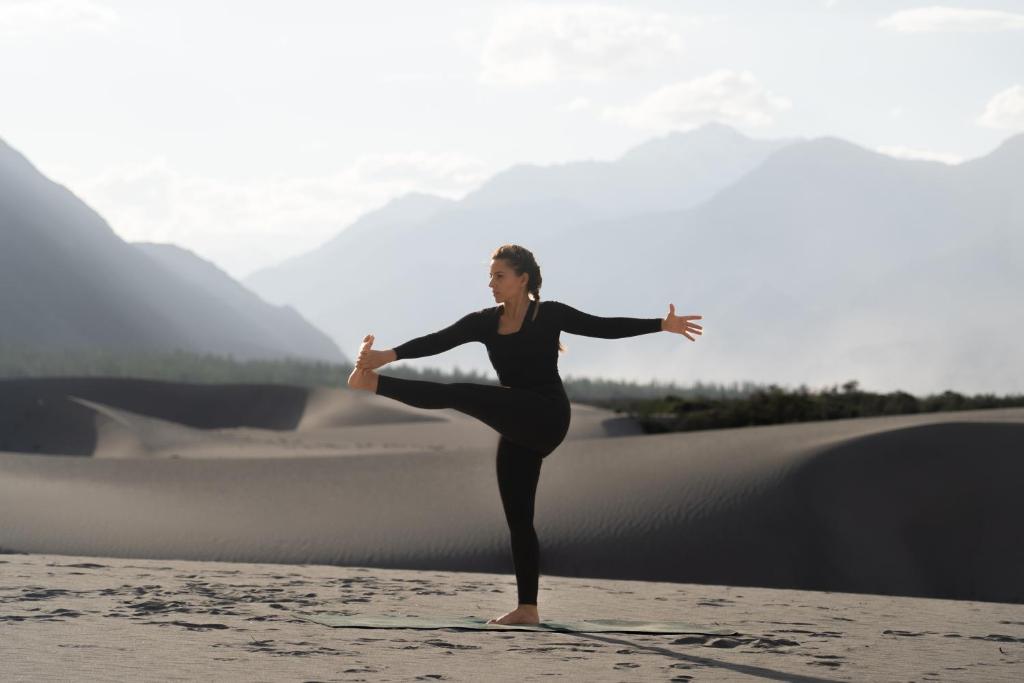 a woman doing a yoga pose on the beach at Stone Hedge Hotel in Nubra