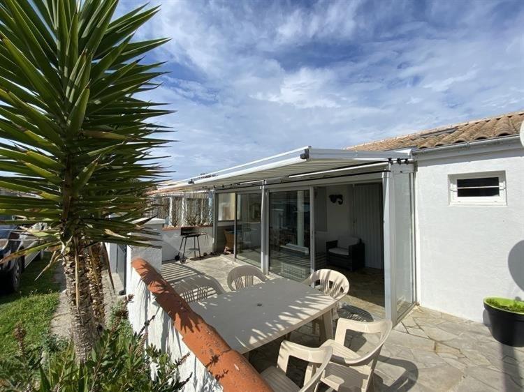 un patio avec une table, des chaises et un palmier dans l'établissement Maison 2 pièces 4 couchages Saint Pierre d'Oléron SPO000-491, à Saint-Pierre-dʼOléron