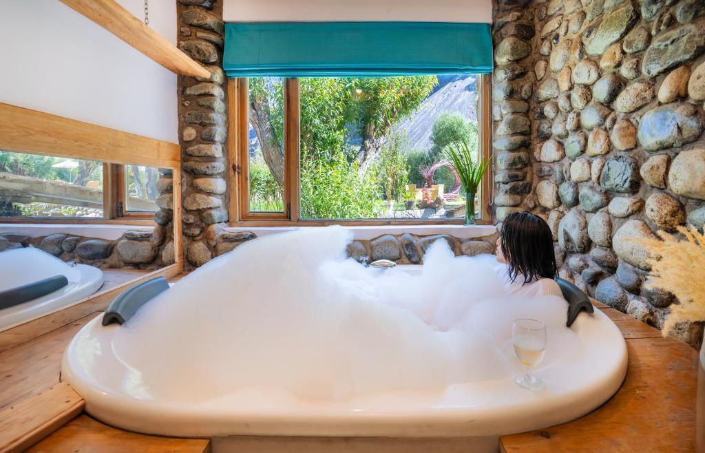 a woman sitting in a bath tub in a room with a window at Stone Hedge Hotel in Nubra