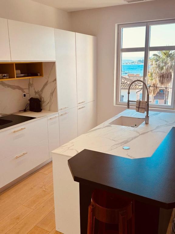 une cuisine avec des armoires blanches et un comptoir noir dans l'établissement Prestige Ste Maxime centre ville, à Sainte-Maxime