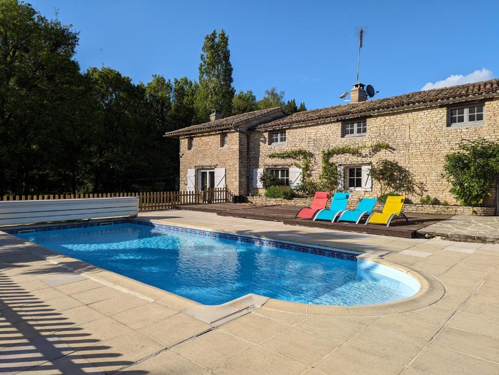 a swimming pool with two colorful chairs in front of a house at La Maison du petit lac in Messé