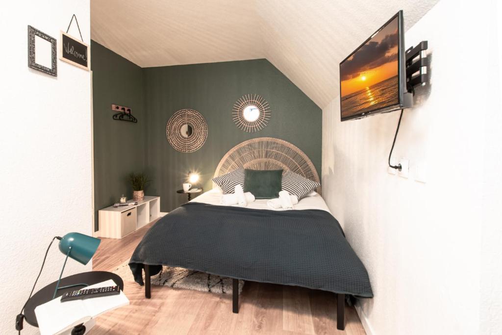 une chambre avec un lit et une télévision sur un mur dans l'établissement Le tiny, à Colmar