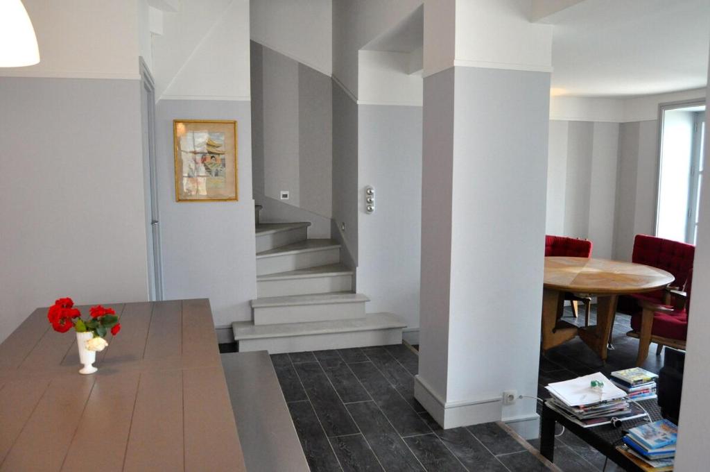 - un salon avec des escaliers et un vase de fleurs dans l'établissement Maison Historique Vue mer exceptionnelle, à Arromanches-les-Bains