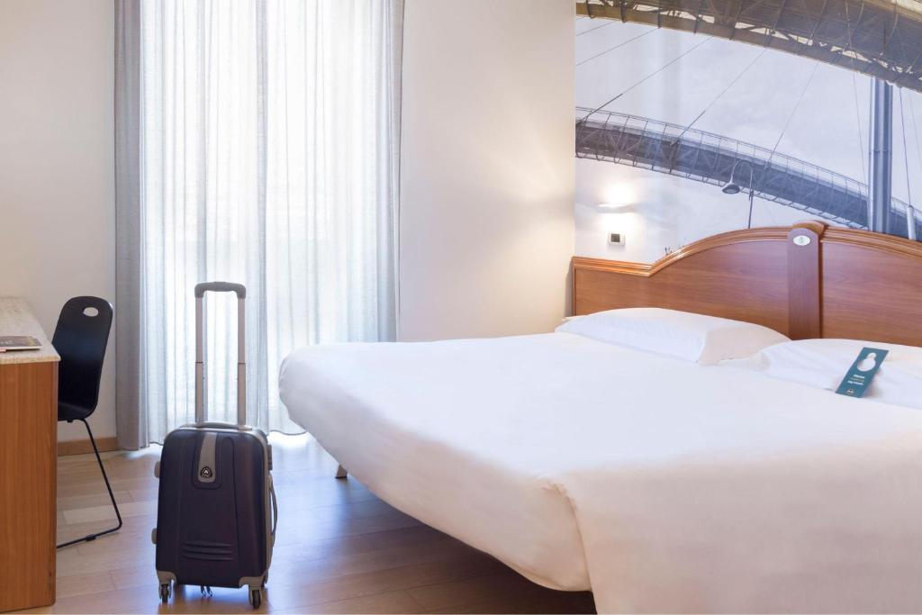 a hotel room with a large bed and a suitcase at B&B Hotel Pescara in Pescara