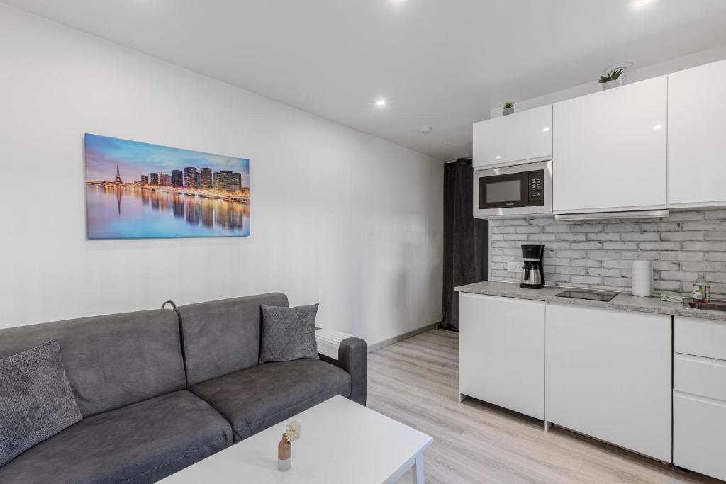 un salon avec un canapé et une cuisine dans l'établissement Orteaux - Cosy studio proche Père Lachaise, à Paris