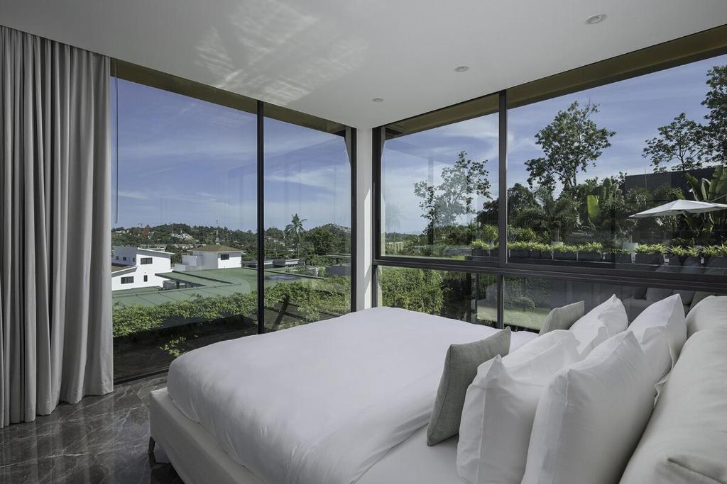 a bedroom with a white bed and a large window at Villa Onyx in Amphoe Koh Samui