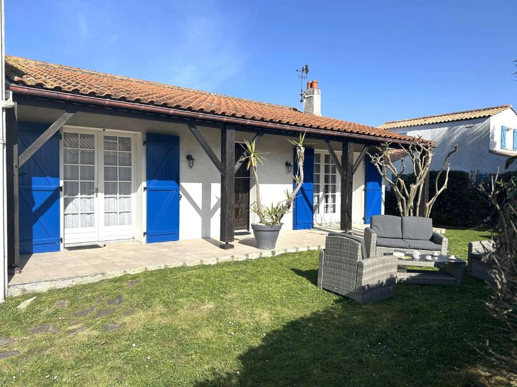une maison avec des portes bleues et une cour dans l'établissement Maison 4 pièces, 7 couchages, proche plage, jardin clos, wifi, calme - Saint-Gilles-Croix-de-Vie - FR-1-224-430, à Saint-Gilles-Croix-de-Vie