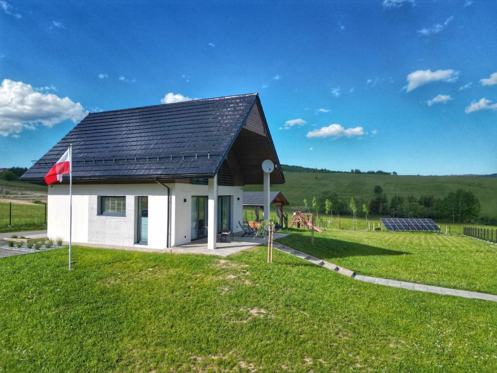 a house with a solar roof on a green field at Lackowa Chill and Rest domki z balią Krynica Zdrój in Krynica Zdrój