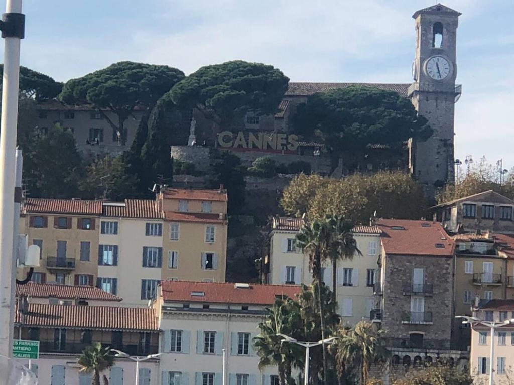 un bâtiment avec une tour d'horloge au sommet d'une colline dans l'établissement Large Studio in Cannes near la Croisette and beach, à Cannes