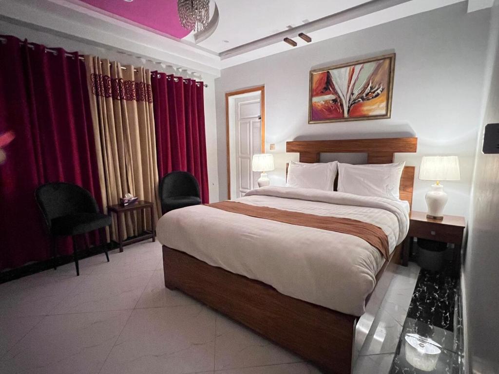 a bedroom with a large bed and red curtains at Nook House - Murree in Murree