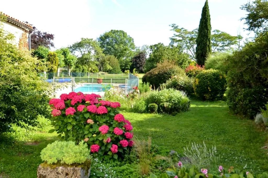 un giardino con fiori rosa e una piscina di Cinégîte du jardin aux étoiles - Proche de Saint Emilion a Saint-Pey-de-Castets