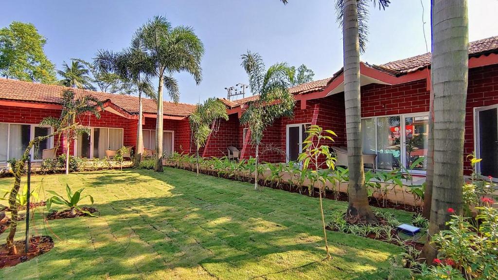 a red house with a yard with palm trees at Whispering Woods Resort in Lonavala