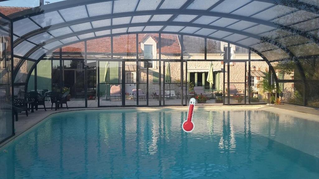 a swimming pool with an archway and a red paddle in the water at La Ferme de Couffy in Couffy