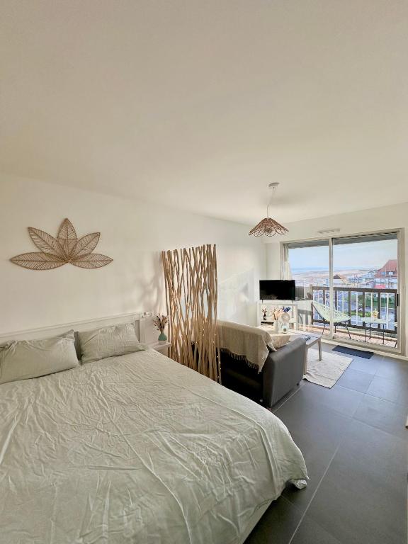 une chambre avec un lit, un canapé et une fenêtre dans l'établissement La Bulle Marine, à Villers-sur-Mer