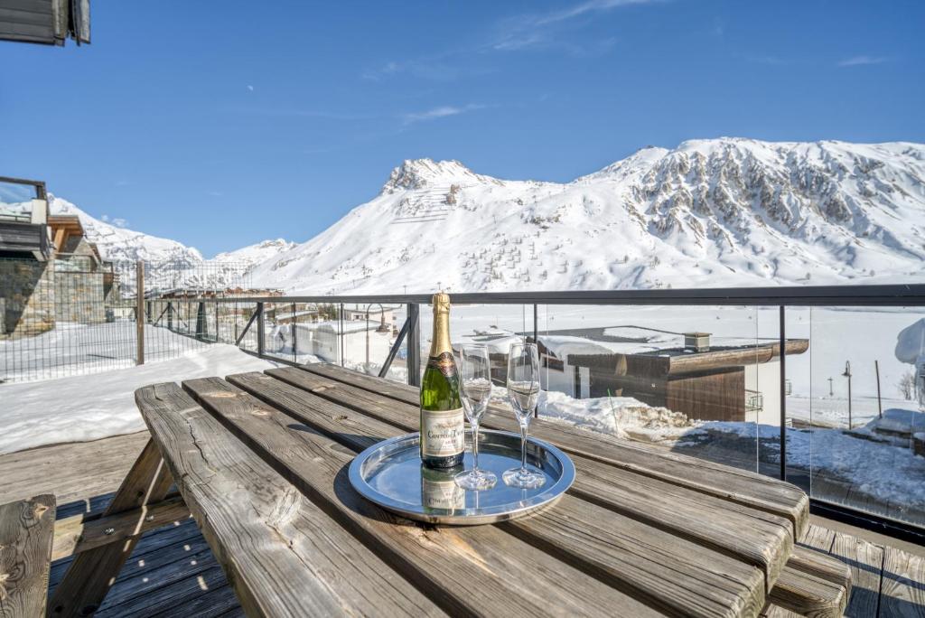a bottle of wine sitting on a wooden table with a glass at Chalet Arktic - Catered Chalet - Sleeps 14 in Tignes