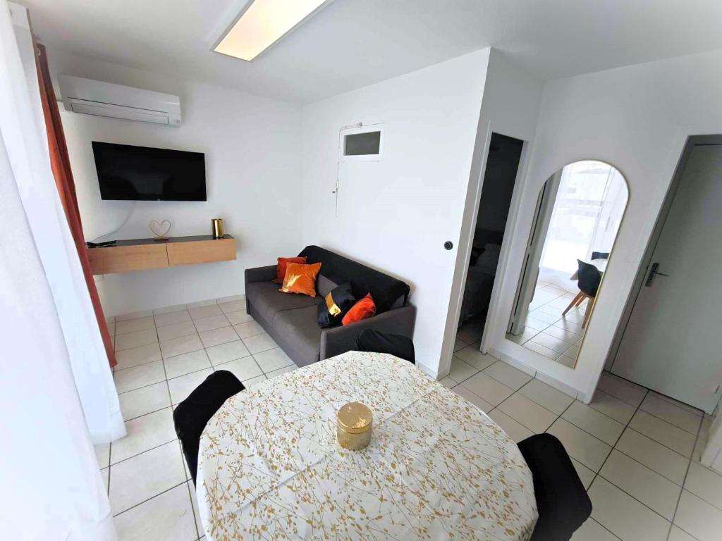 un salon avec une table et un canapé dans l'établissement Appartement Village Naturiste Concupiscence, au Cap d'Agde