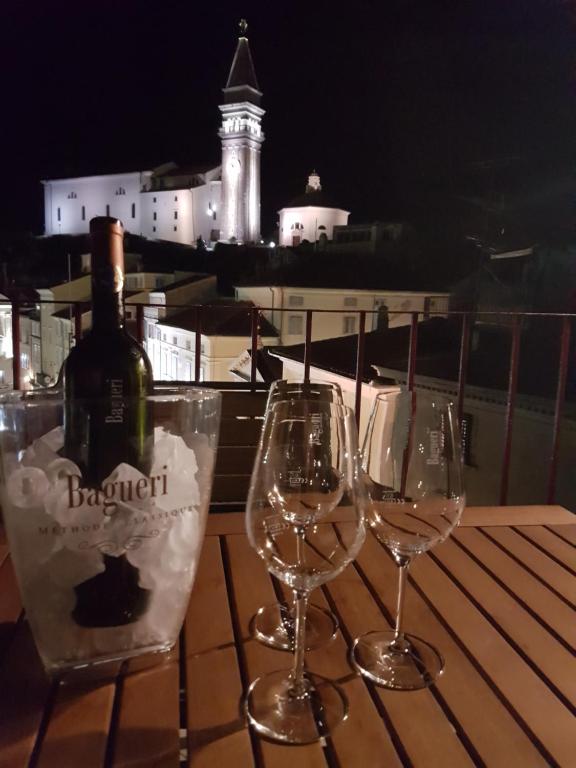 two wine glasses sitting on a table with a bottle of wine at Apartment Tartini Piran exclusive rooftop penthouse in Piran