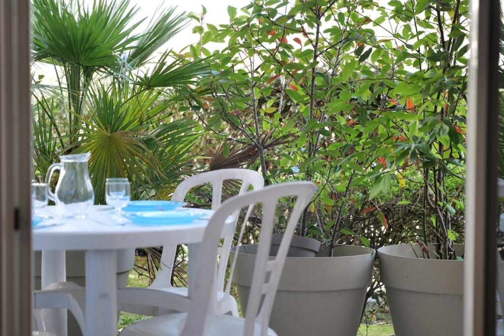 une table et des chaises blanches ainsi que quelques plantes dans l'établissement Appartement pour 2-4 personnes piscine commune et parking privatif, à Les Sables-dʼOlonne