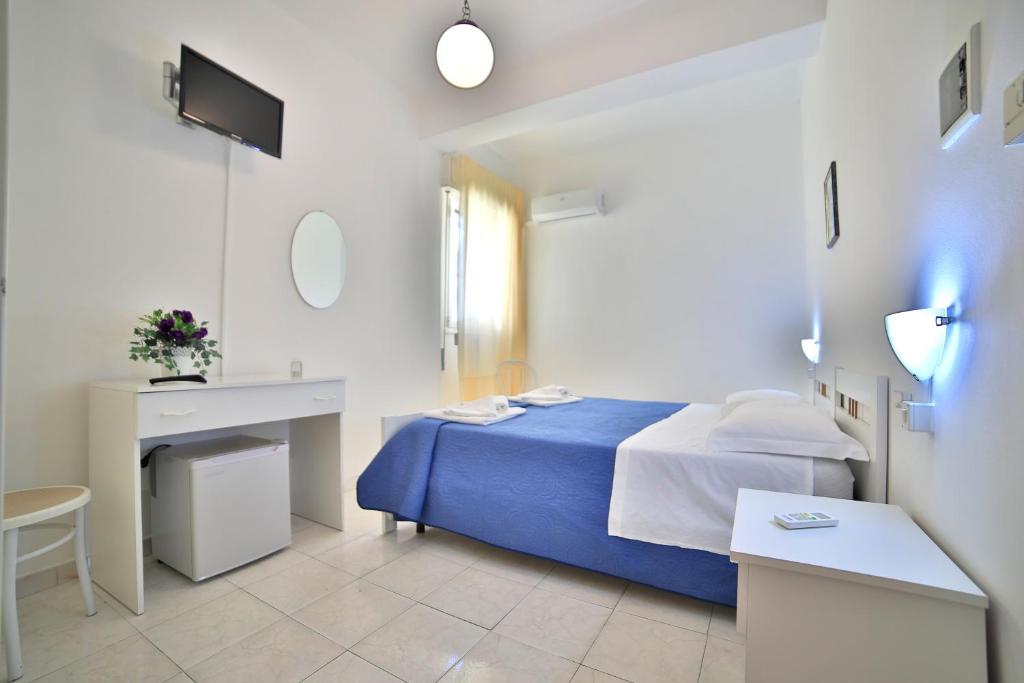 una camera bianca con letto blu e scrivania di Hotel da Ettore - Salento Selection a Porto Cesareo