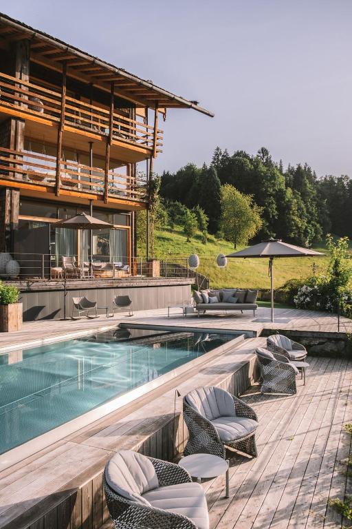 ein Swimmingpool mit Liegestühlen und einem Sonnenschirm in der Unterkunft Der Jägersberg in Fischen im Allgäu