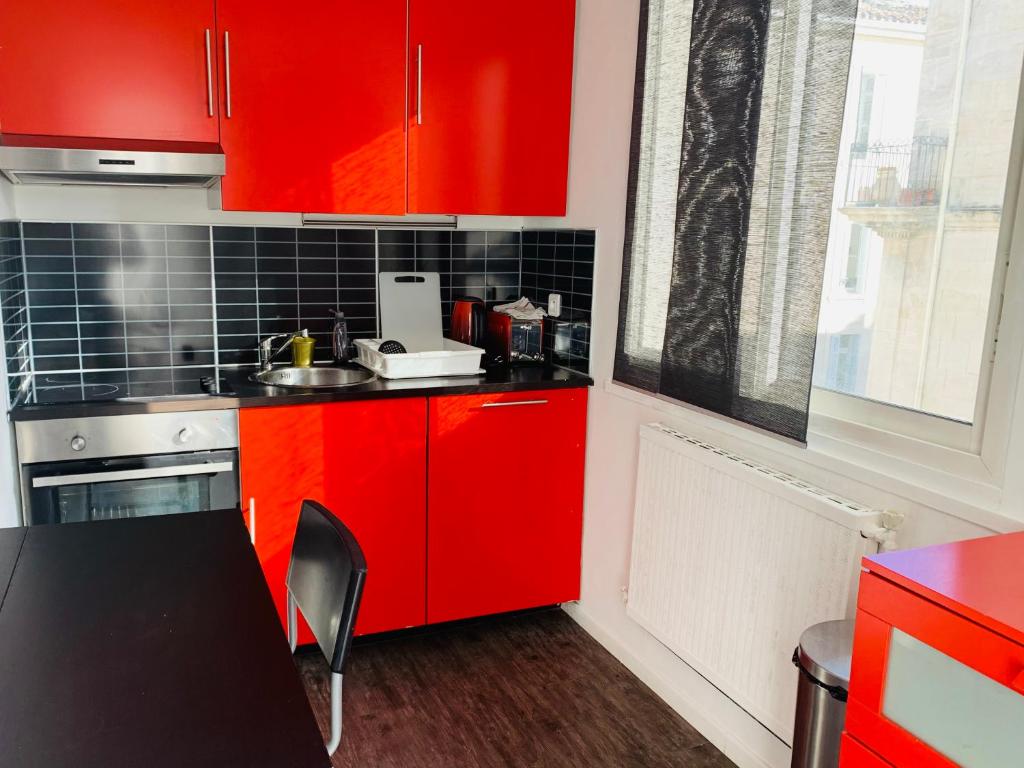 une cuisine rouge avec des placards rouges et une table dans l'établissement Terrasse au pied de la gare, à Marseille